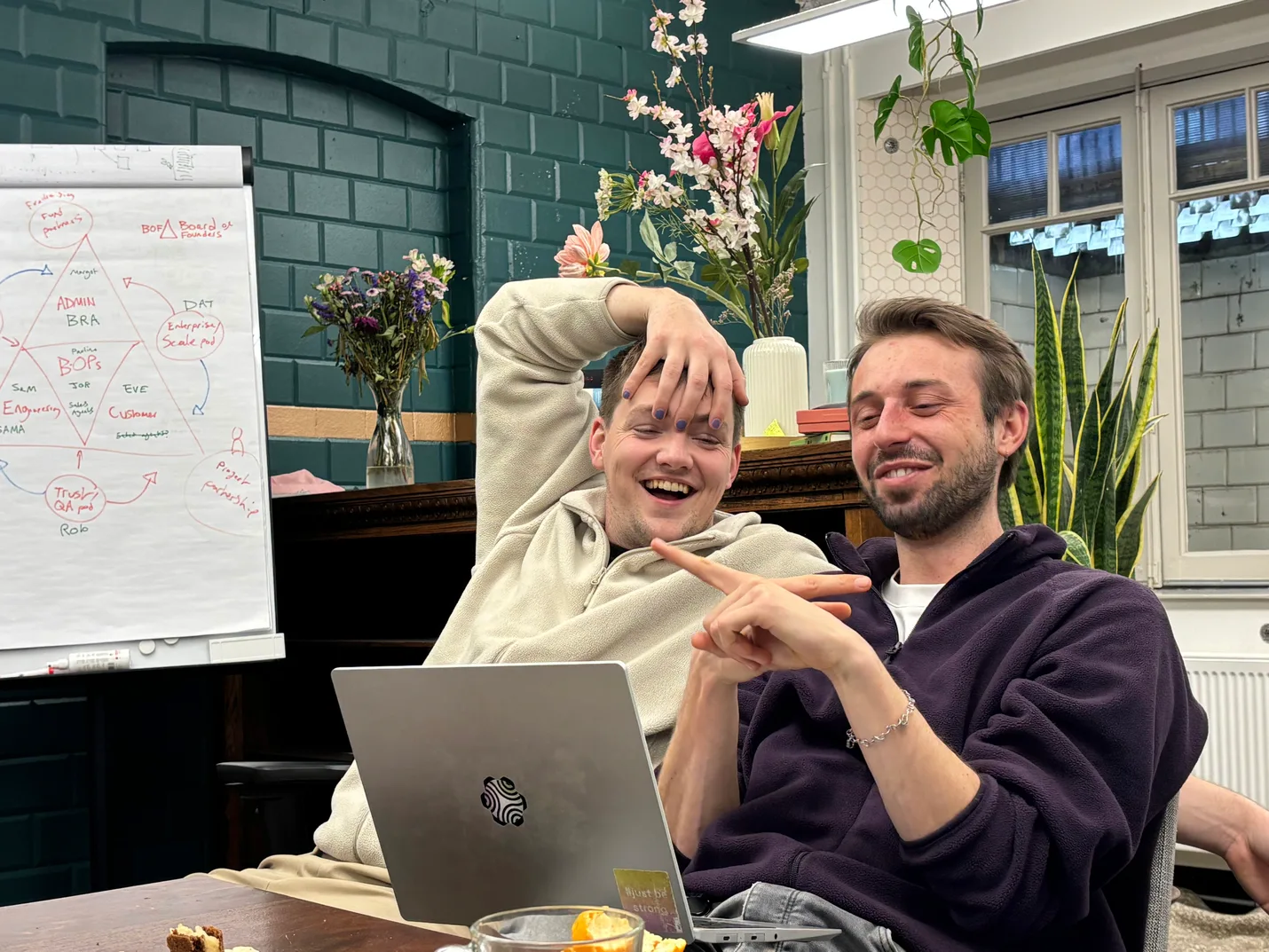 Two dembrane colleagues laughing over a laptop in the office